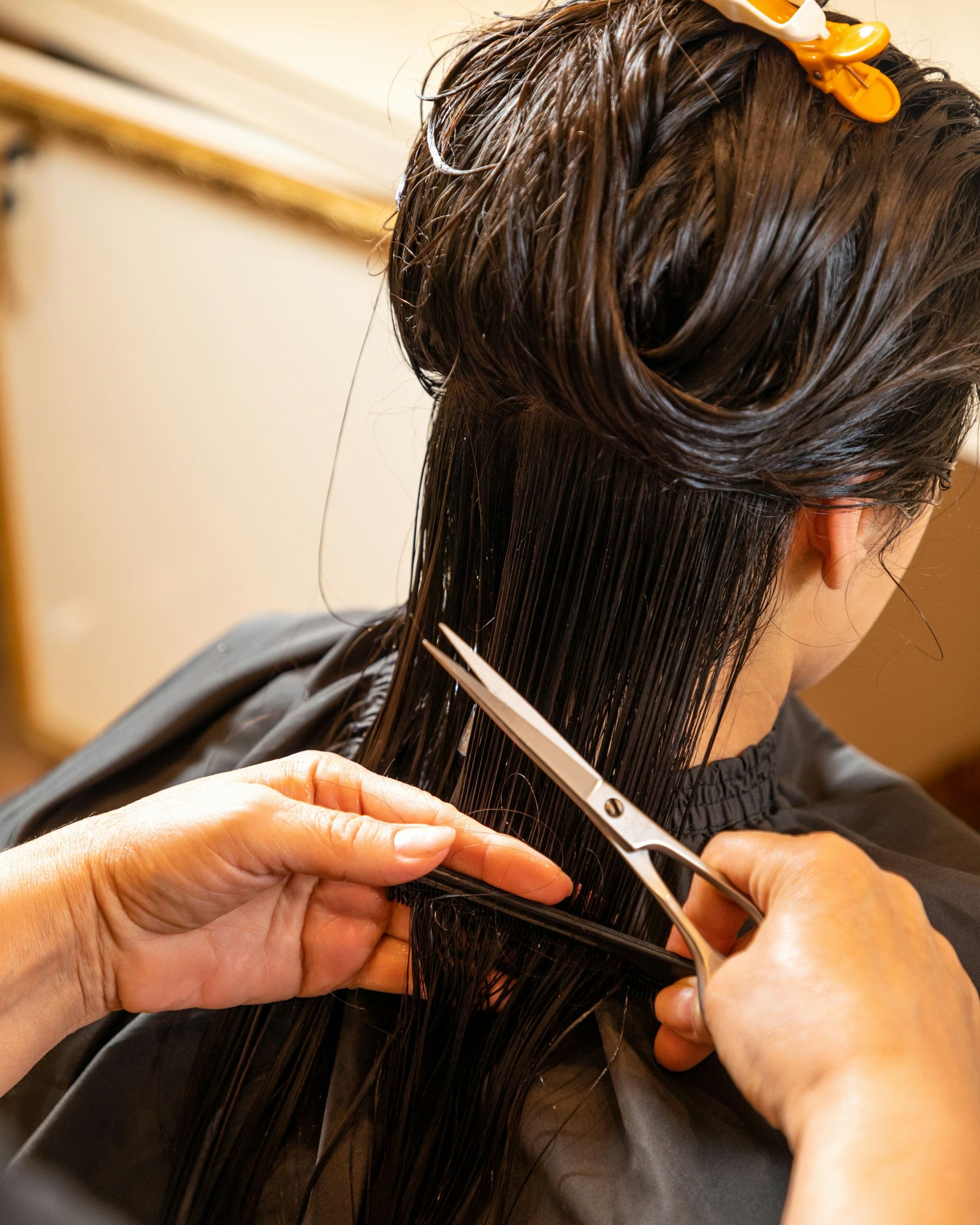 Une coiffeuse coupe de longs cheveux bruns mouillés, peigne et ciseaux en main