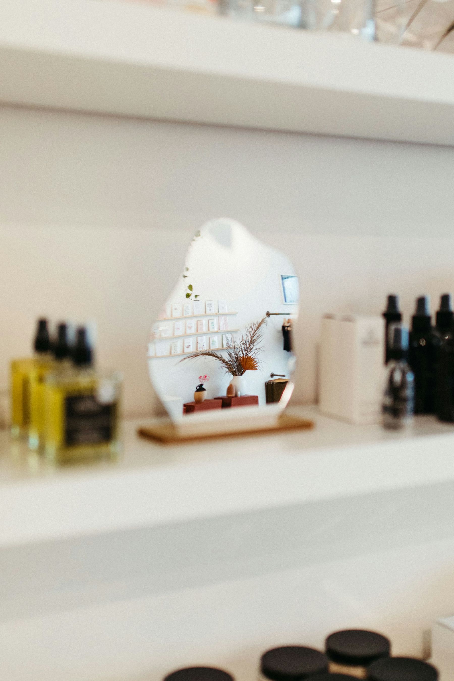 Étagère du salon avec flacons d’huile, produits de soin et petit miroir